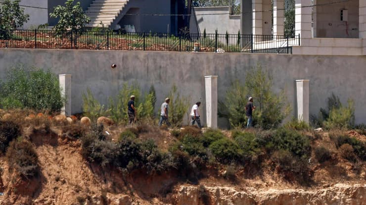 מתנחלים מול בתי פלסטינים בכפר קוסרה (צילום: Zain JAAFAR / AFP) מתנחלים מול בתי פלסטינים בכפר קוסרה