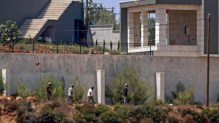"תקיפות יומיות והטרדות". מתנחלים בקוסרה (צילום: Zain JAAFAR / AFP) מתנחלים מול בתי פלסטינים בכפר קוסרה