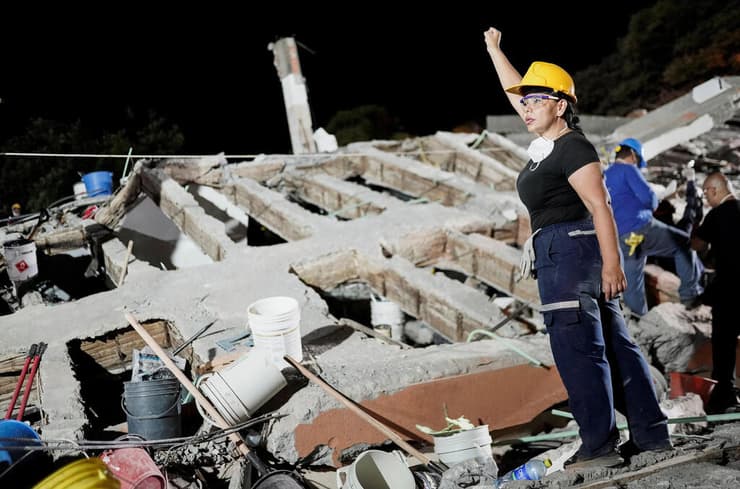 אחת המחלצות מניפה את אגרופה, הסימן שבעזרתו מאותתים אנשי כוחות ההצלה לחבריהם להשתתק - בניסיון לשמוע קריאות לעזרה ואותות חיים בהריסות (צילום: REUTERS/Sergio Acero) קולומביה רעידת אדמה רעש הריסות קאלי אשת הצלה מניפה יד כדי לסמן שקט בניסיון לשמוע קולות