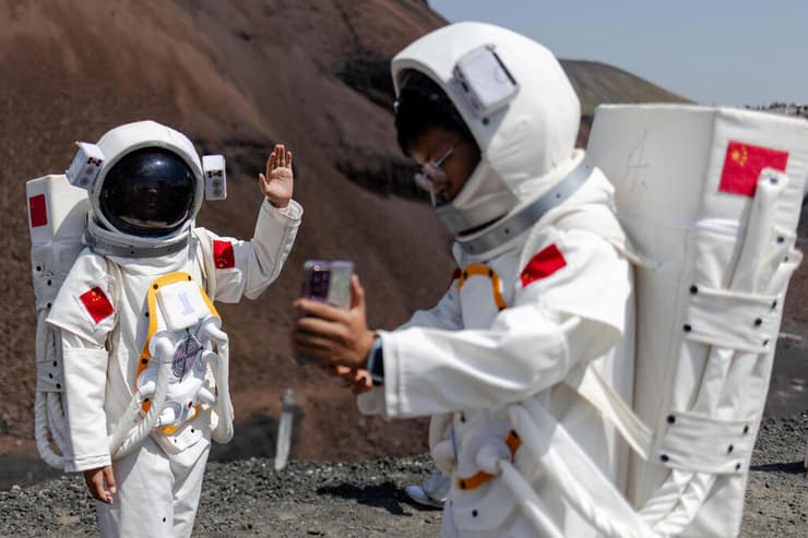 REUTERS/Maxim Shemetov תיירים בחליפות אסטרונאוטים מצטלמים בפארק הגעשי וולנהאדה, מונגוליה הפנימית, סין