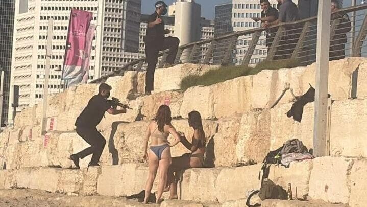 מאבטח מכוון את נשקו על מתרחצים 