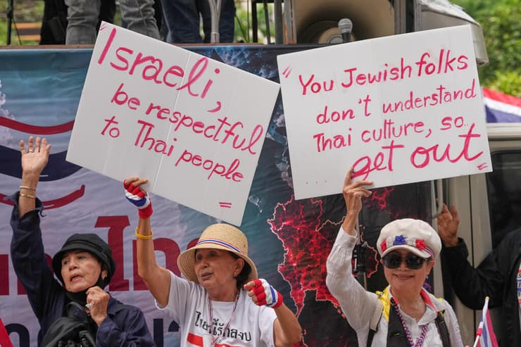"אתם היהודים לא מביבים את התרבות שתאילנדית, אז צאו החוצה" (AP Photo/Sakchai Lalit) מפגינים נושאים שלטים במהלך מחאה מול שגרירות ישראל בבנגקוק