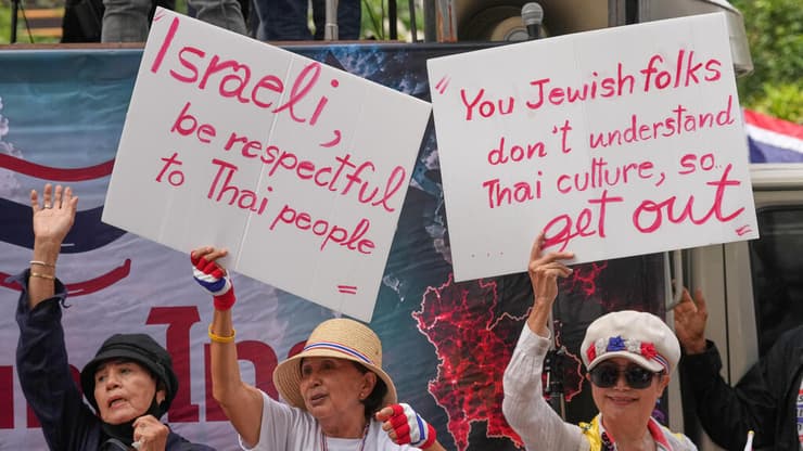 "אתם היהודים לא מבינים את התרבות התאילנדית, אז צאו החוצה"(AP Photo/Sakchai Lalit) (AP Photo/Sakchai Lalit) מפגינים נושאים שלטים במהלך מחאה מול שגרירות ישראל בבנגקוק