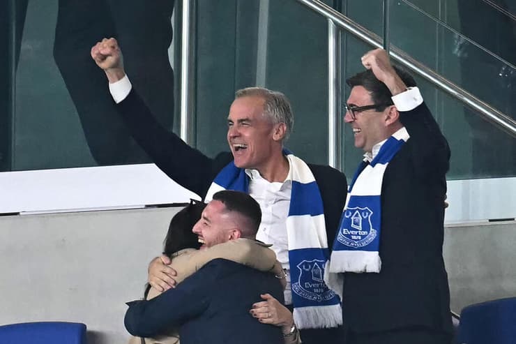 צילום: Paul ELLIS / AFP 16 בספטמבר ראש ממשלת קנדה מארק קרני וראש ממשלת בריטניה אנדי ברנהאם במשחק גביע הליגה האנגלית ב כדורגל בין אברטון ל וולברהמפטון וונדררס באצטדיון בליברפול