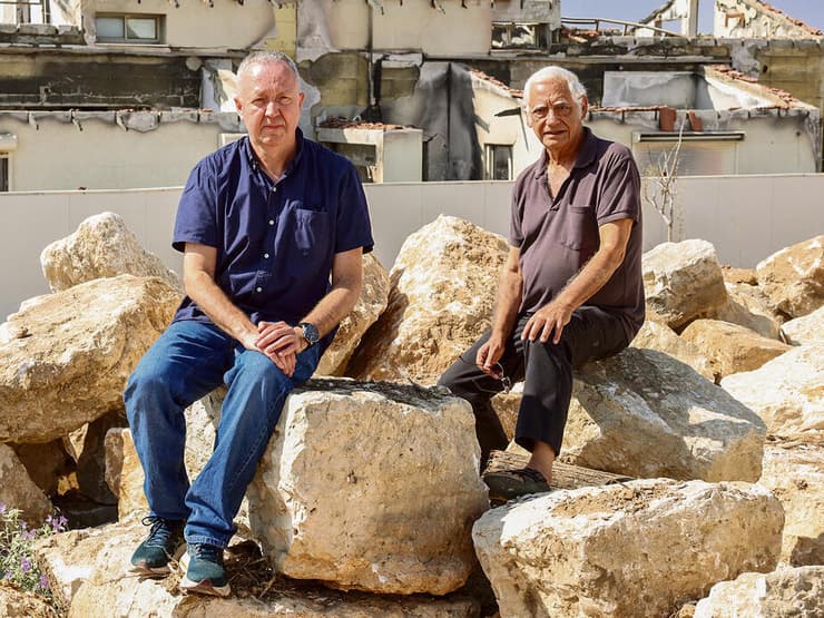 מימין: מנצ'ר מבארי ופרופ' אריאל פלדשטיין ממפלסים, ליד הבית היחיד שנותר עומד בשכונות הכרם והזיתים בבארי (גדי קבלו) מימין: אברהם דבורי (מנצ'ר) מבארי ופרופ' אריאל פלדשטיין ממפלסים ליד הבית היחיד שנותר עומד בשכונות הכרם והזיתים בבארי
