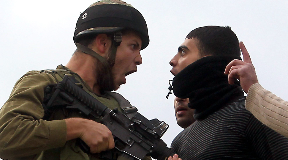 An IDF soldier confronts a Palestinian man in the West Bank 