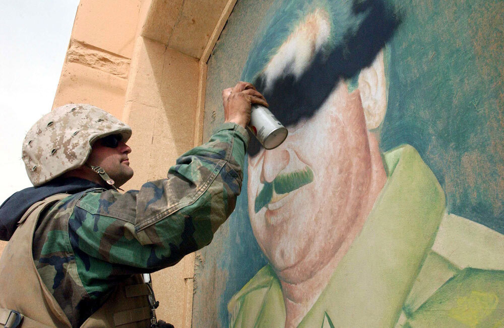 U.S. soldier spray paints over image of Saddam Hussein
 in 2003 