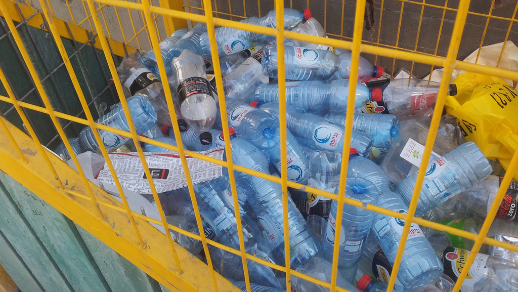 Пустые бутылки в уличном контейнере для сбора тары 
