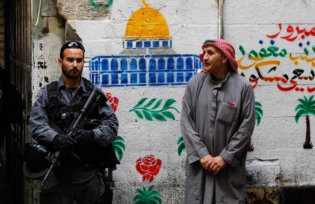 A Border Police officer stands next to a local Muslim resident in East Jerusalem 