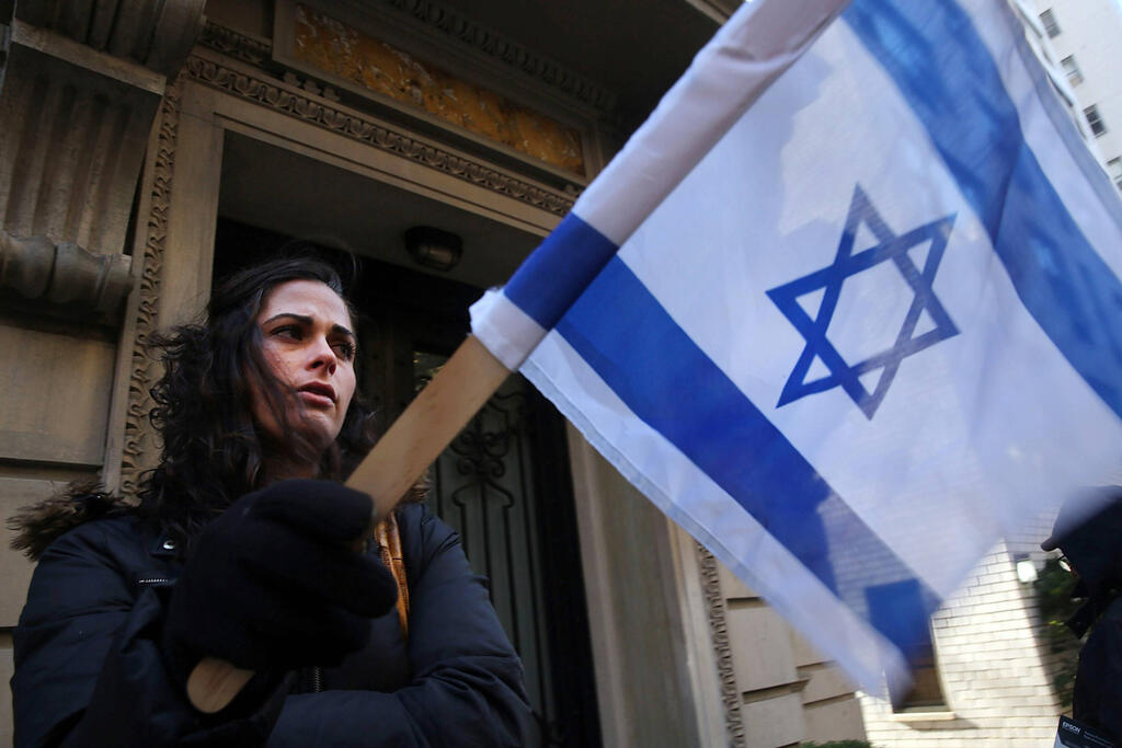 An American Jewish woman holds an Israeli flag during a protest 