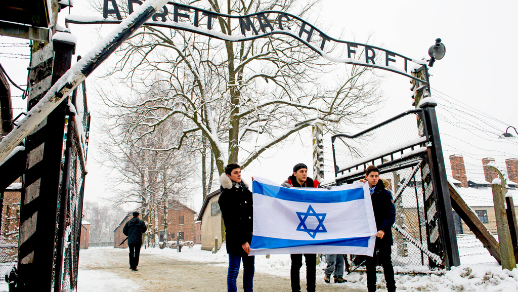 Youths holding the Israeli flag in front of the gate to the Auschwitz concentration camp 
