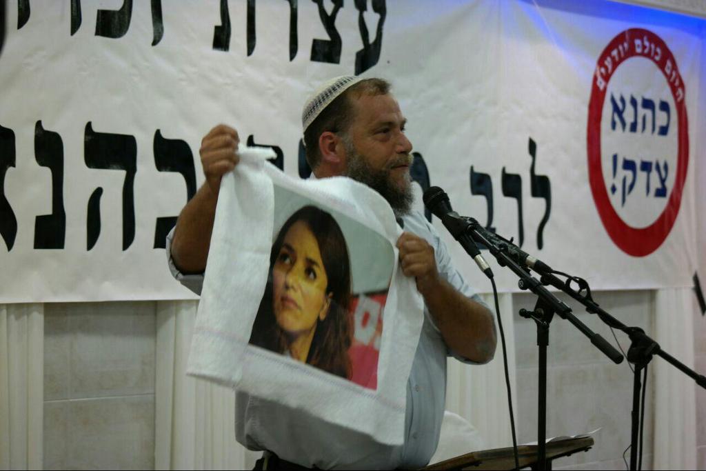 Benzi Gopstein during a memorial service for Meir Kahane, holding in protest a picture of Arab-Israel media personality Lucy Aharish 