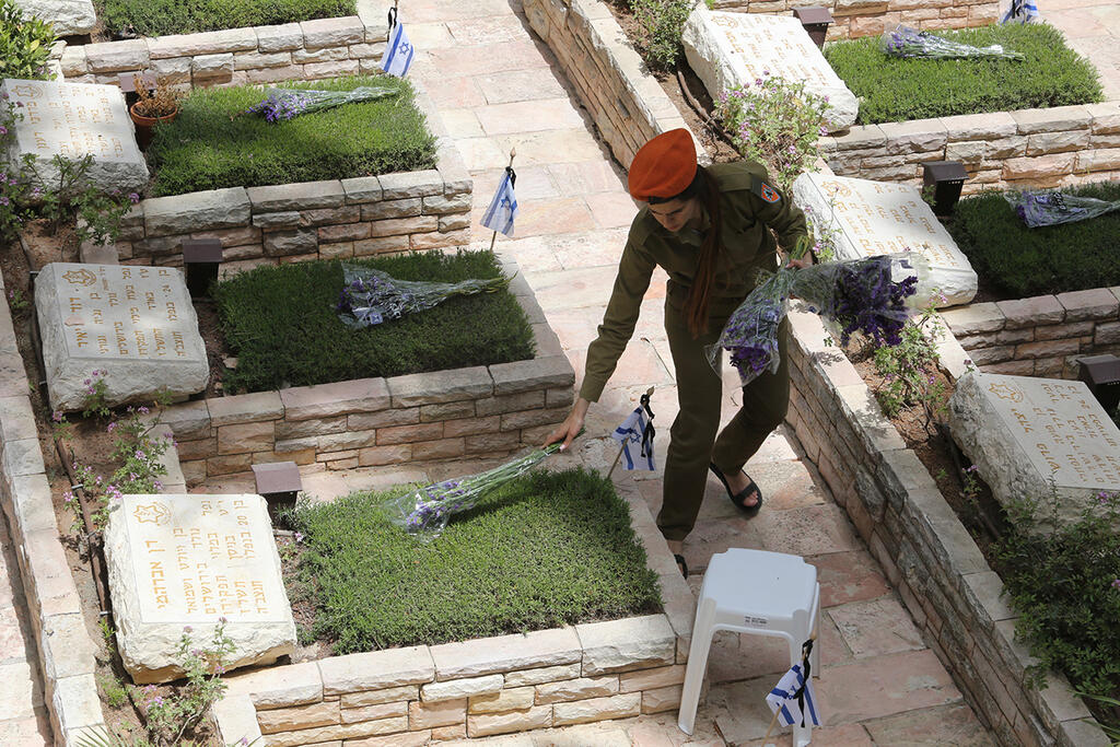 Soldier lays flowers on soldiers' graves in the national military cemetery on Mount Herzl 