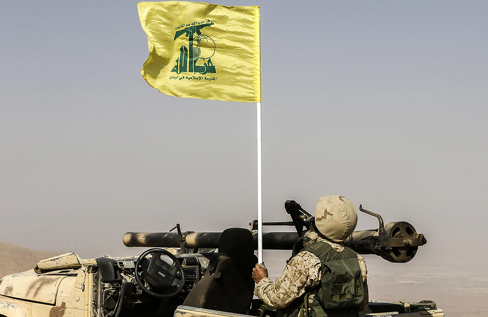 A Lebanese soldier holding the Hezbollah flag near the Lebanon-Syria border 