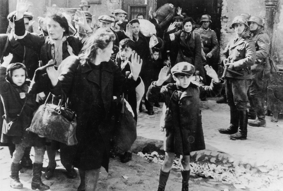 Boy holds his hands over his head while SS soldier points a submachine gun in his direction during the 1943 Warsaw Ghetto uprising 