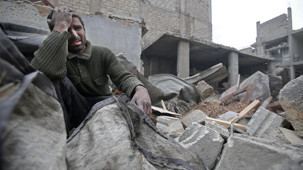 A Syrian man mourns over his destroyed home in Arbin in the eastern Ghouta region of Syria
