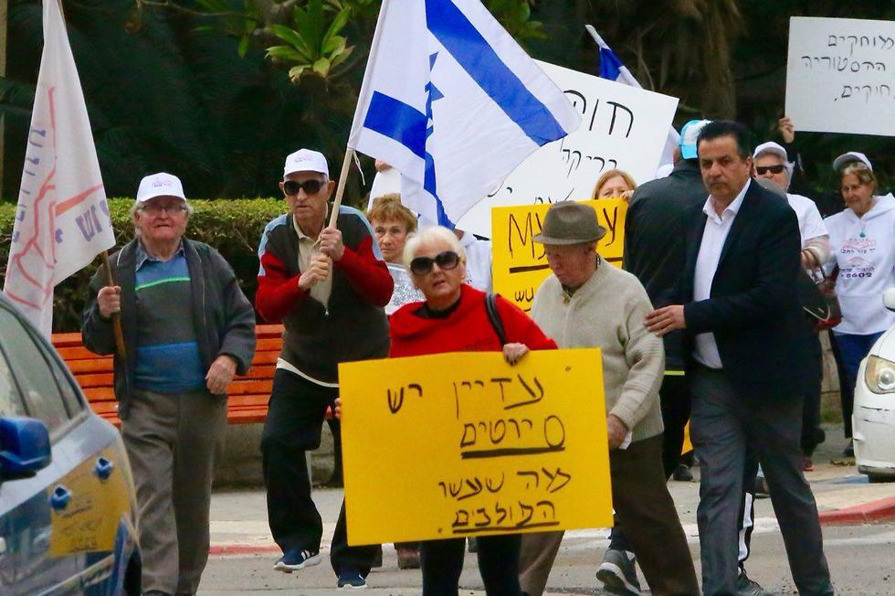 Holocaust survivors hold banners and wave an Israeli flag during a protest in front of Polish embassy in Tel Aviv on February 8, 2018, against a controversial bill that made it a crime to hold Poland responsible for Nazi crimes
