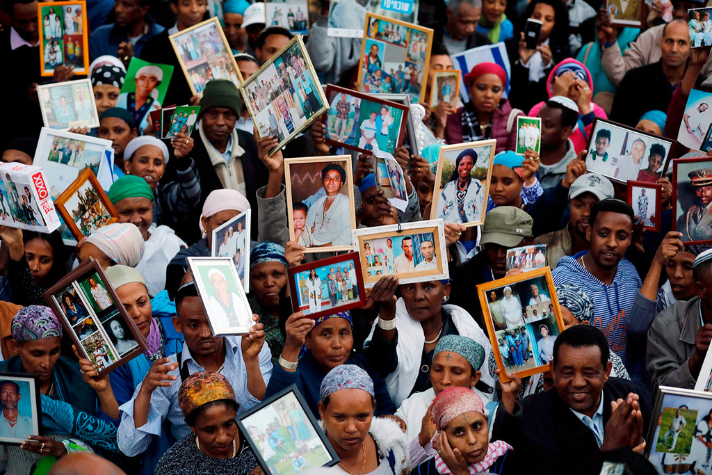 Israeli Ethiopians hold pictures of relatives waiting in Ethiopia to immigrate to Israel, in front of Knesset in Jerusalem, March 12, 2018 