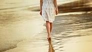 אישה צועדת על חוף הים 