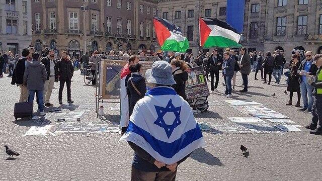 יהודי באמסטרדם שמפגין לבדו עם דגל ישראל ענק מול הפגנות הסתה של ה- BDS