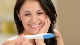 אישה מחייכת עם בדיקת היריון