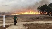 ילד רוכב על אופניים על רקע שריפה בעוטף עזה