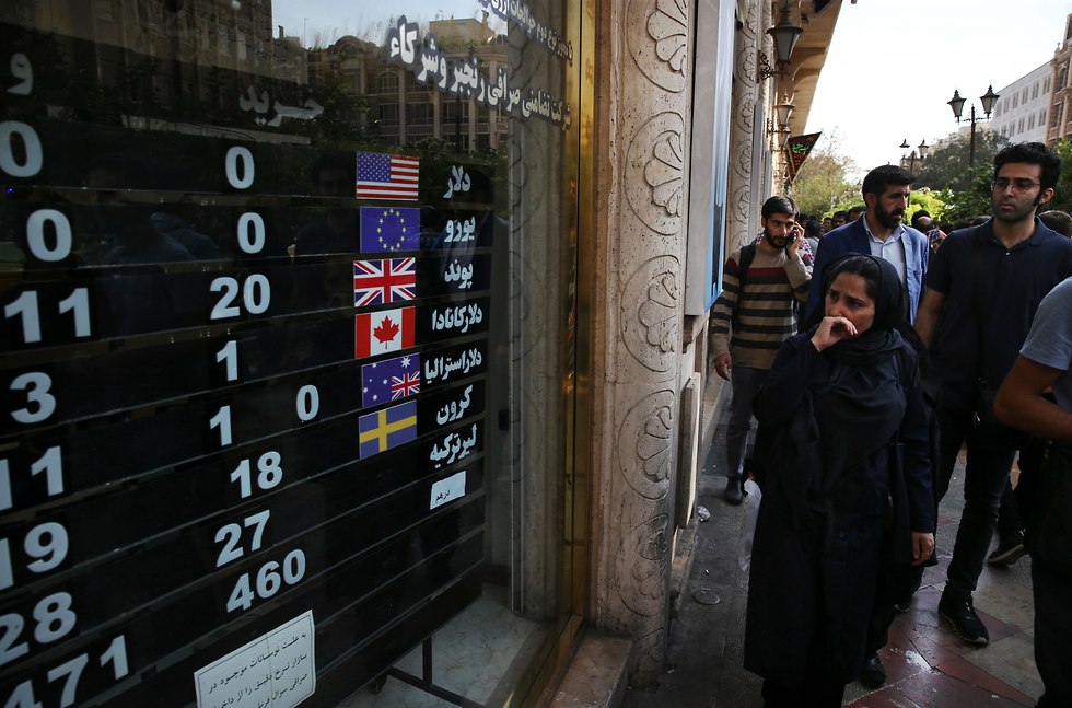 איראנים במרכז טהרן מתבונננים בשערי מטבעות שונים בחודש שעבר