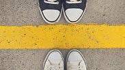 שתי זוגות נעליים ניצבות אחת מול השנייה עם קו ביניהן