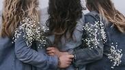 צעירות מחובקות מחזיקות פרחים מאחורי הגב