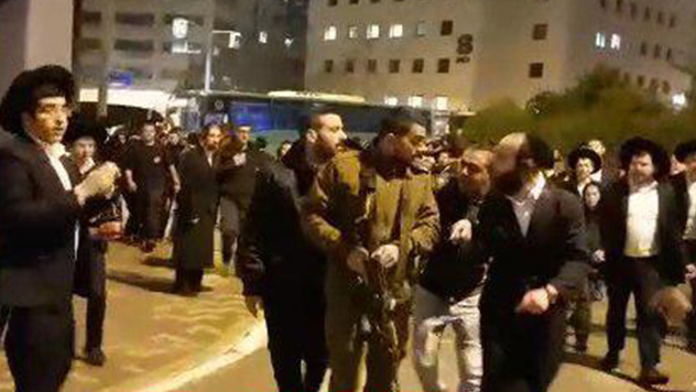 חייל מכוון נשק לעבר מפגינים המתנגדים לגיוס חרדים לצה"ל בירושלים