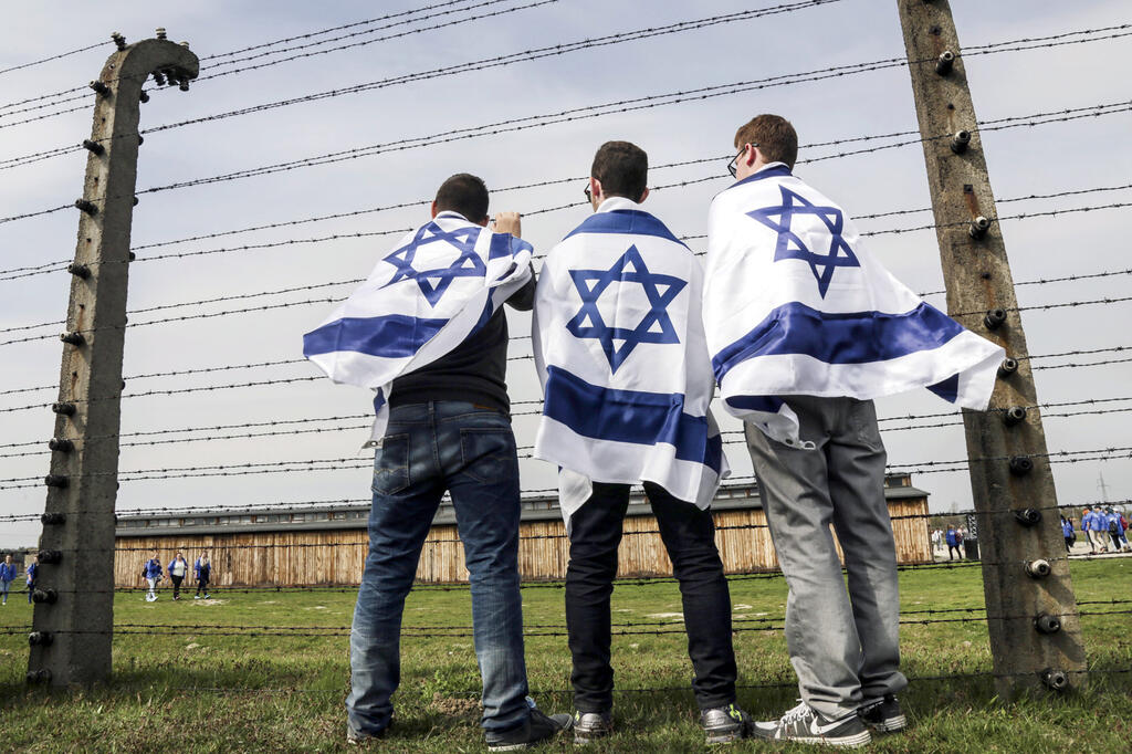 Students wrapped in the Israeli flag at former Nazi death camp during a Holocaust study trips in Poland (Photo: Shutterstock) לאשה