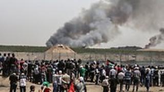 פלסטינים ב גבול עזה מביטים על שריפה בשדה בצד הישראלי