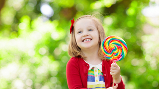 ילדה עם סוכריה על מקל מלאה בצבעי מאכל