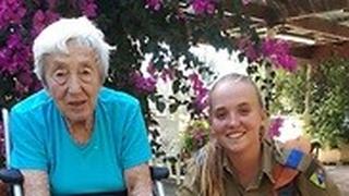 החיילת אודליה באייר עם קשישה בבית האבות לניצולי שואה שמשפחתה הקימה