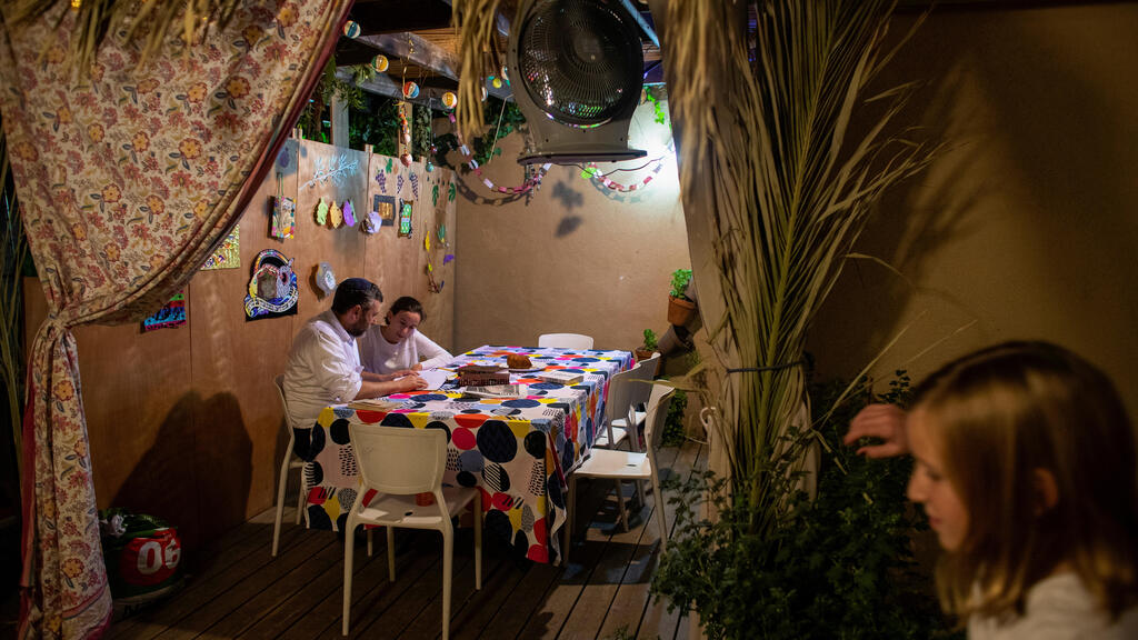 Yoni Stanleigh and his daughter Nehora sit in their sukka