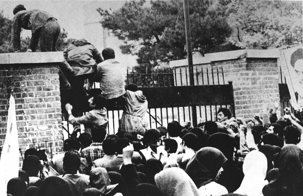 Iranian revolutionary students climb the U.S. embassy's gate in 