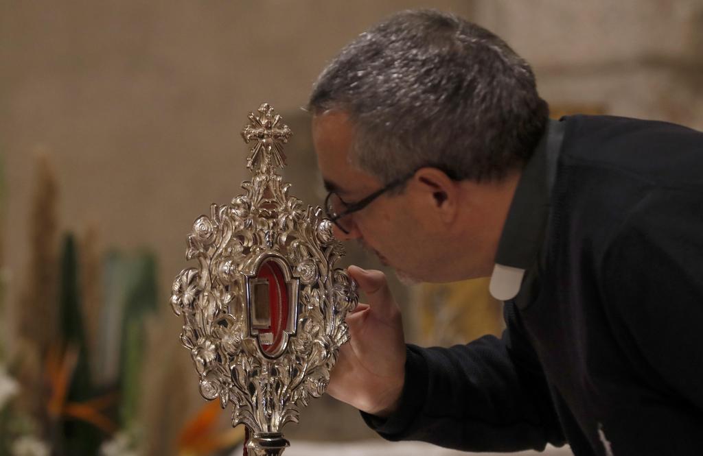 A Christian pilgrim touches a small piece of a wooden relic believed to be from Jesus' manger at the Notre Dame church in Jerusalem, Nov. 29, 2019 