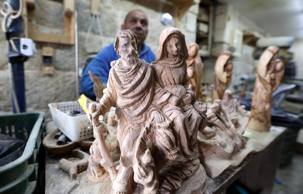 A Palestinian carpenter works on a wooden sculpture of Christian religious figures at a workshop in the West Bank city of Bethlehem, Dec. 8 2019