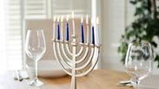 חנוכיה דולקת לצד כוסות יין