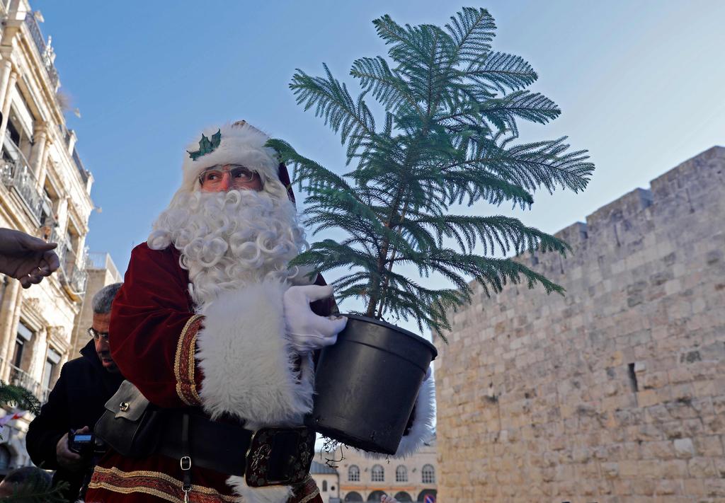 Jerusalem Santa holds a potted plant