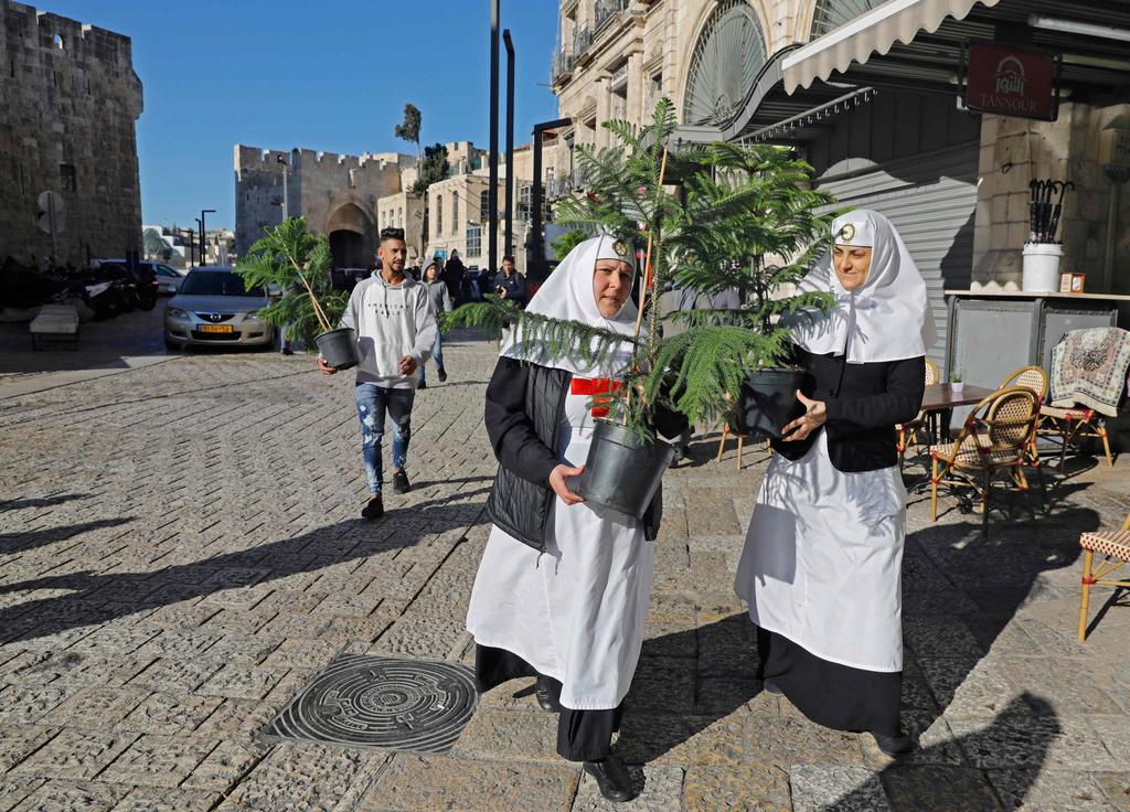Eastern Orthodox nuns walk with potted plants in Jerusalem's Old City