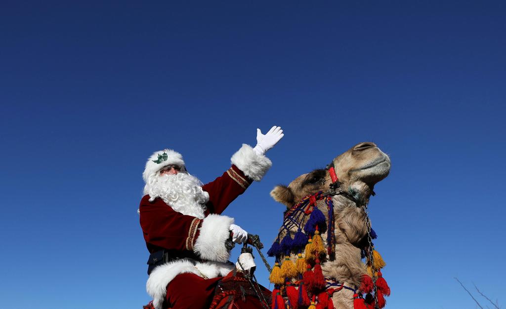 Issa Kassissieh wears a Santa Claus costume as he rides a camel