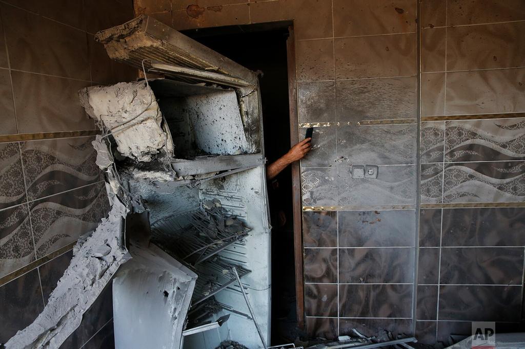 A local resident uses his mobile phone to take photos of the damage in a house caused by a mortar fired from inside Syria on the Turkish town of Akcakale 