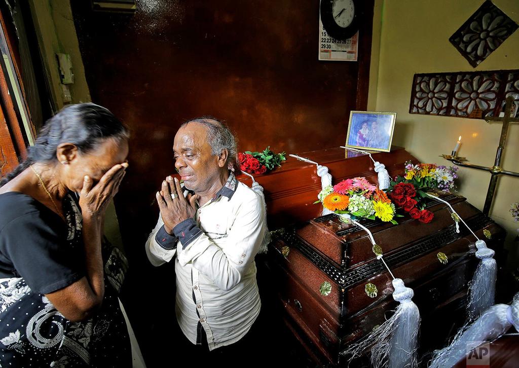 A Sri Lankan family mourns next to the coffins of their three family members, all victims of an Easter Sunday bombing, in Colombo, Sri Lanka 