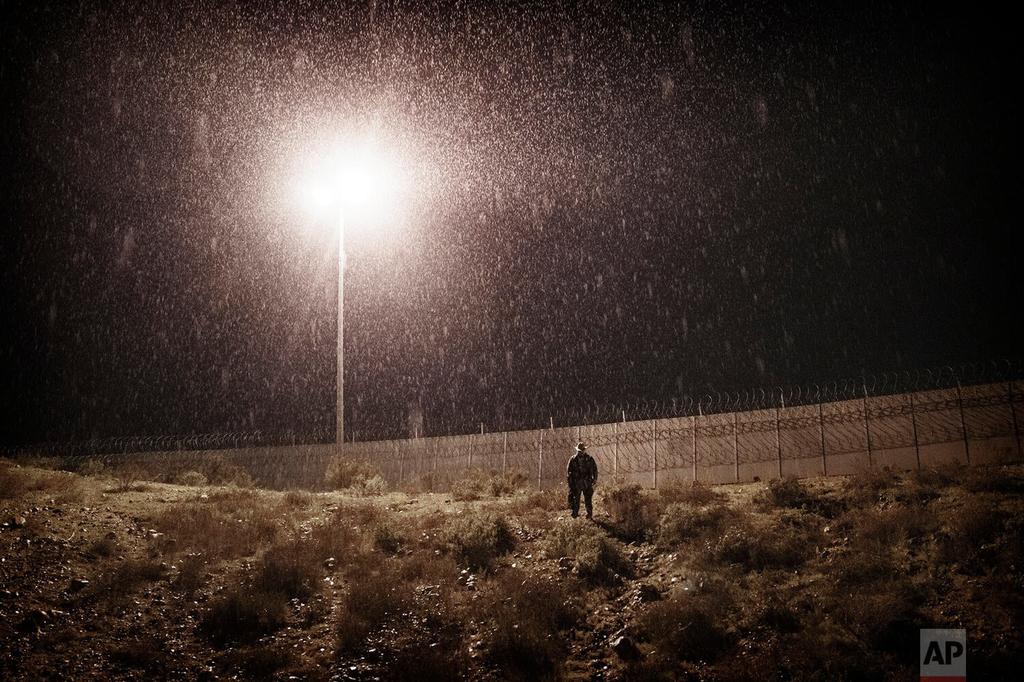 A U.S. Border Protection officer stands in heavy rain near the border fence between San Diego, California, and Tijuana, Mexico 