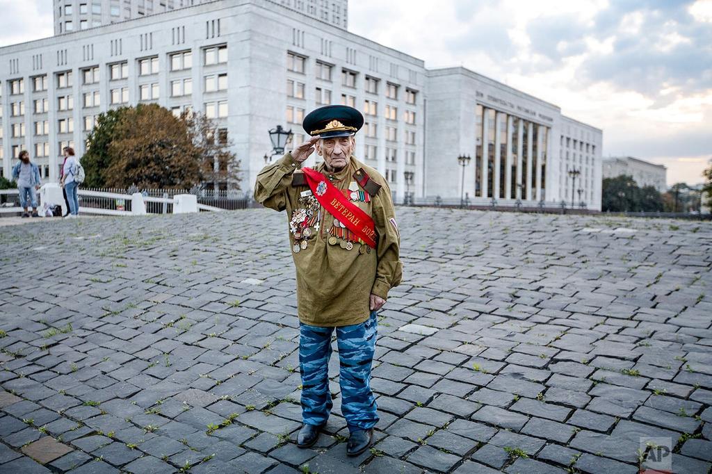 World War II veteran Lev Yatsevich, 92, salutes as he waits for other participants of an event marking the anniversary of the failed August 1991 hardline coup outside the former Russian parliament building, which now houses the Russian Cabinet, in Moscow  