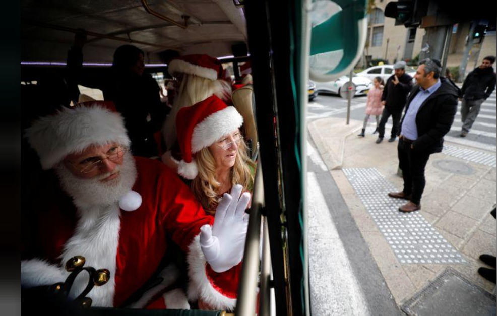People dressed in Santa Claus outfits wave from inside a bus as they make their way to visit Jerusalem's Old City as a group of Santa Clauses from around the world 
