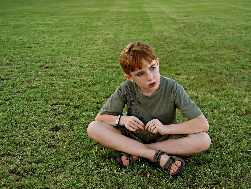 ילד אוטיסט בוהה בדשא 