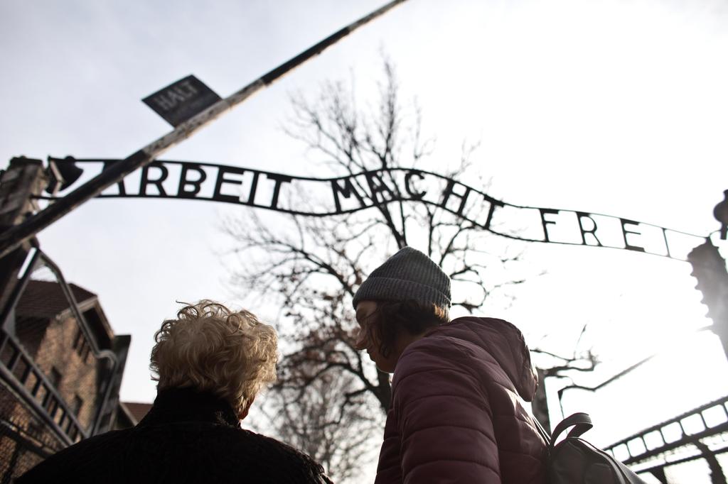 Jona Laks, survivor of Dr. Josef Mengele's twins experimentsand her granddaughter, Lee Aldar stand next to the gate with the slogan "Arbeit macht frei" 