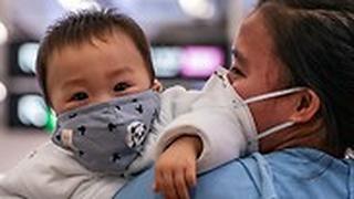 אישה עם תינוק בתחנת רכבת מסיכות 